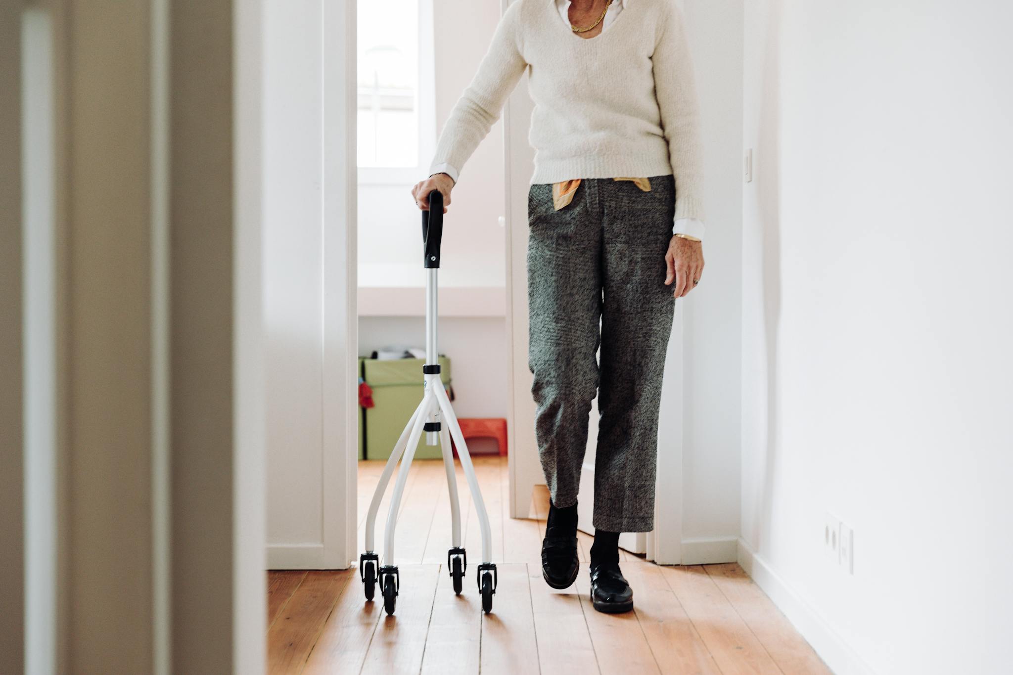 Senior adult walking indoors with a rollator, promoting mobility and independence.